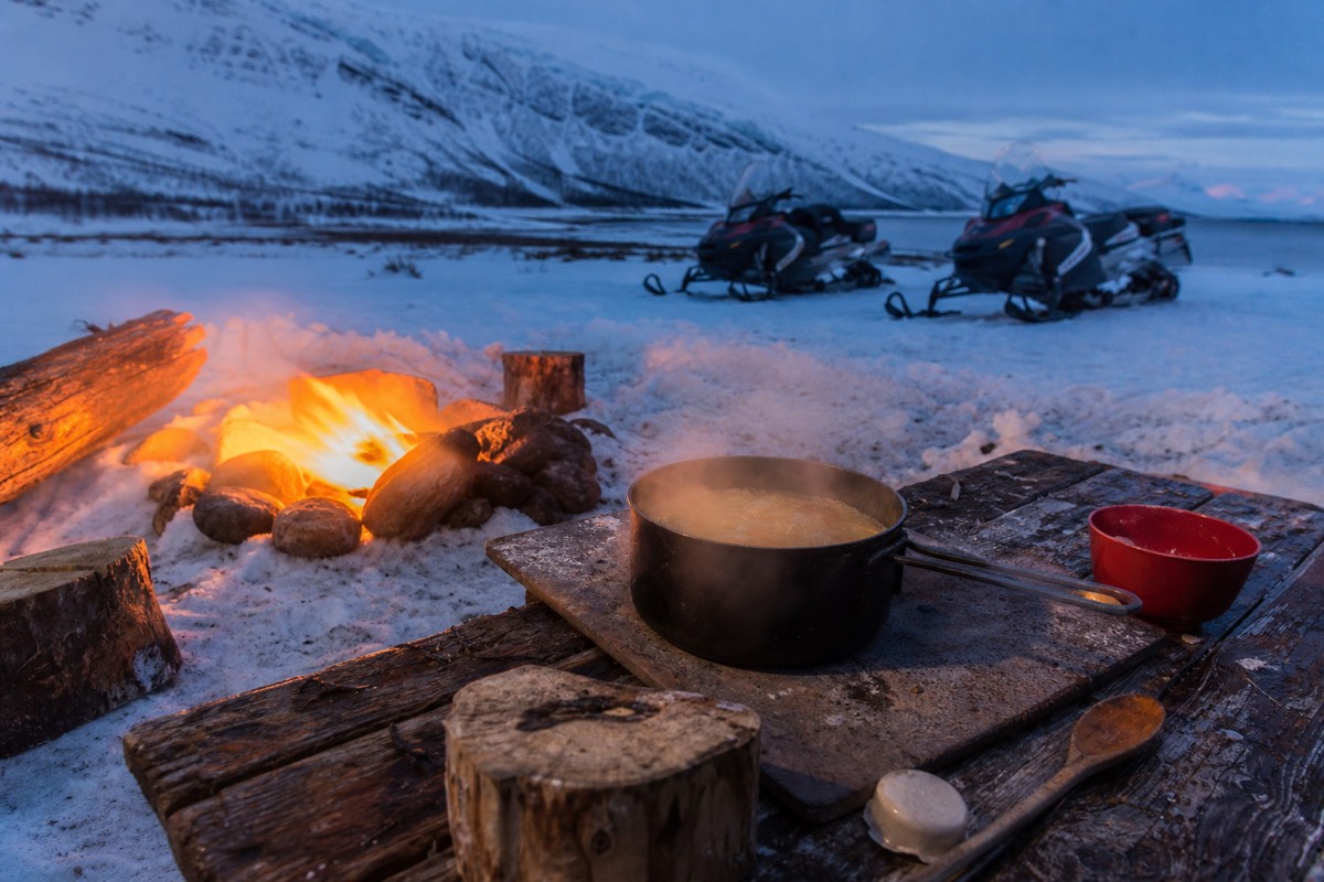 A warm soup and campfire stop at an Arctic snowmobile base camp